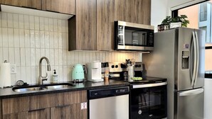 Una cocina moderna con armarios de madera, electrodomésticos de acero inoxidable, lavavajillas y microondas.
