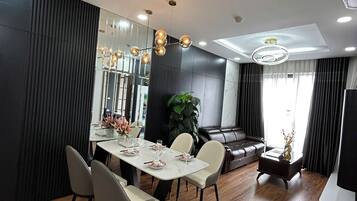 A modern dining area with a wooden table, white chairs, and a chandelier.