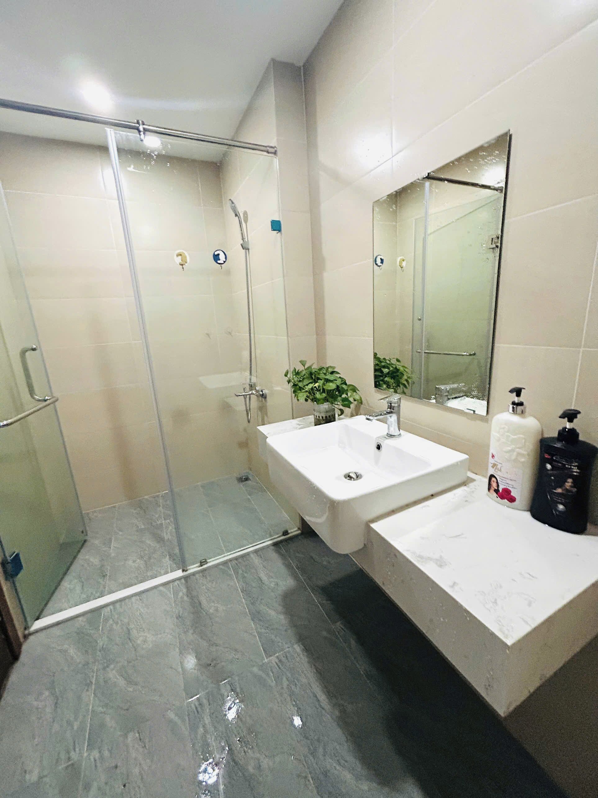 A modern bathroom with a glass-enclosed shower, dual sinks, and a large mirror.