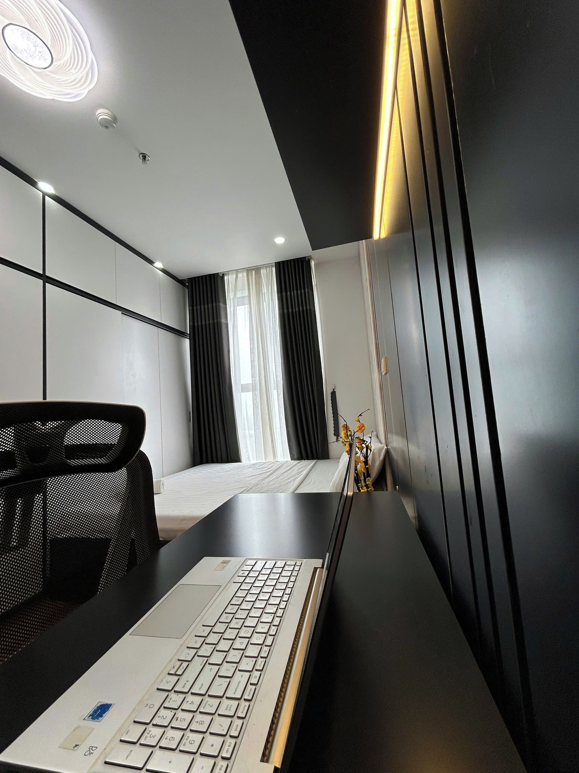 A modern hotel room with a desk, a bed, and a large mirror.