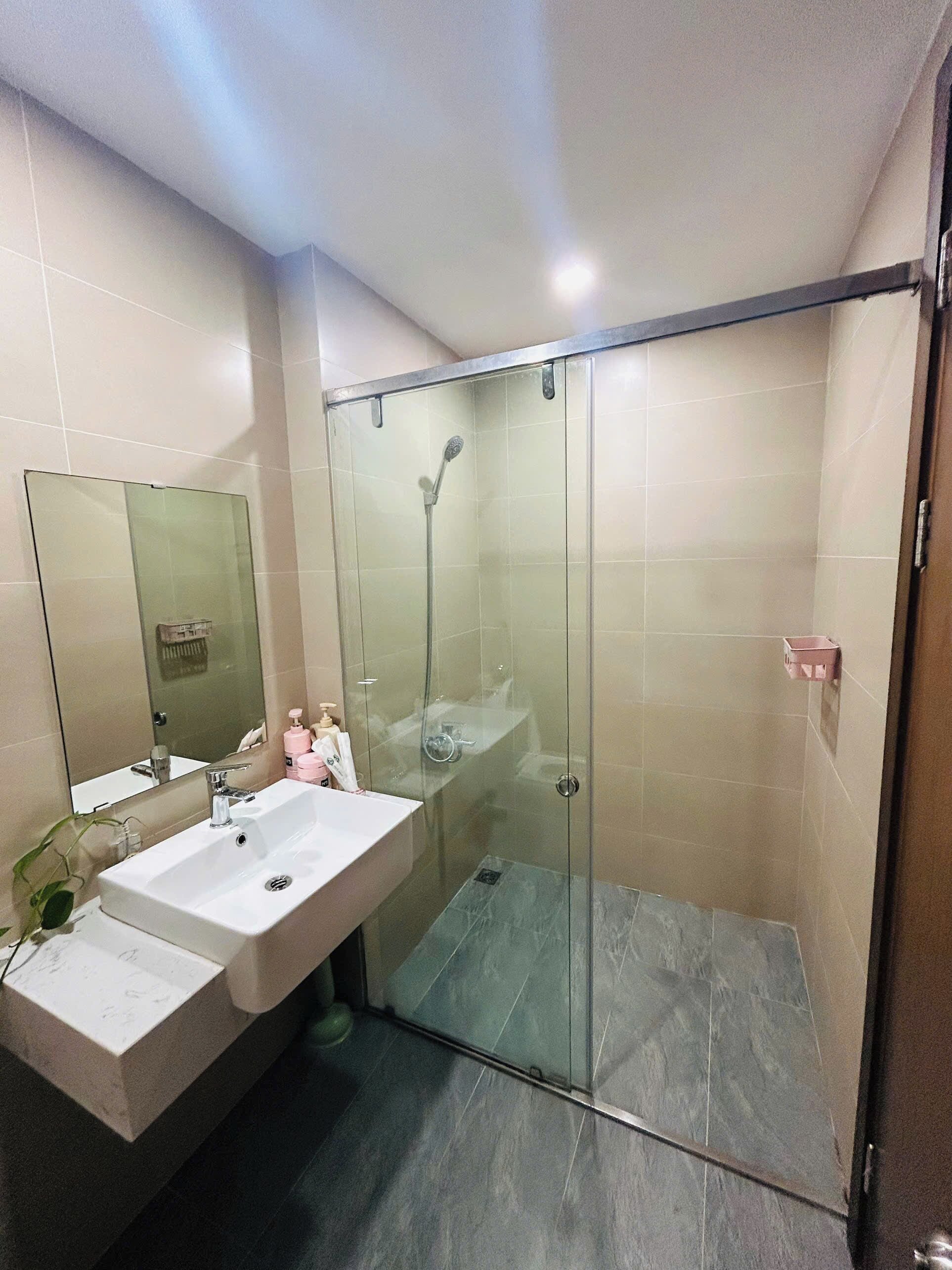 Un bany modern amb dutxa de vidre, un lavabo gran i un mirall.
