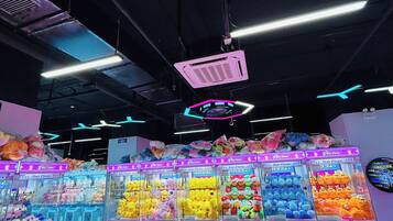 A brightly lit arcade area with claw machines filled with plush toys.