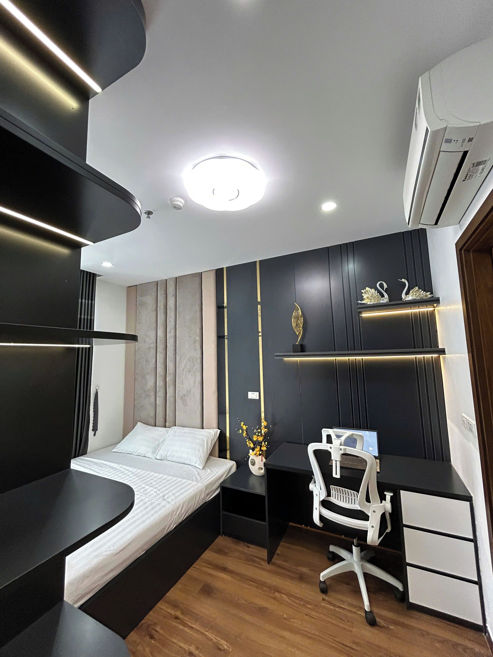 A modern bedroom with a bed, desk, chair, and decorative items.