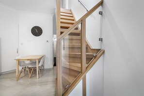 A modern interior with a wooden staircase, a dining area with chairs, and a wall clock. - Brisbane Terrace - Hobart Inner City (Hobart)