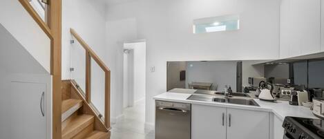 A modern kitchen with a dishwasher, stove, and white cabinetry.