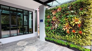 A modern building entrance with a glass door, a tiled floor, and a vertical garden wall. - Ama's House Luxury Boutique Hotel (Chiang Mai)