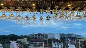A restaurant with hanging wine glasses and a view of the cityscape. - Ama's House Luxury Boutique Hotel (Chiang Mai)