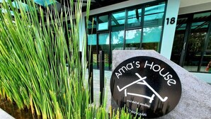 A sign for Ama's House with a modern building in the background. - Ama's House Luxury Boutique Hotel (Chiang Mai)