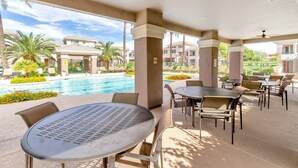 A covered outdoor area with tables and chairs, a pool, and a view of residential buildings. - Kierland Commons Shops & Dining, Hiking, Fitness room, Gated, Heated Pool & Spa + FREE GOLF & MORE! (Scottsdale)