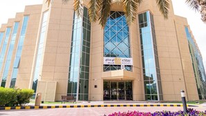 A modern hotel building with a large glass facade, a prominent entrance, and palm trees framing the entrance. - eStay Hotel  (Dubai)