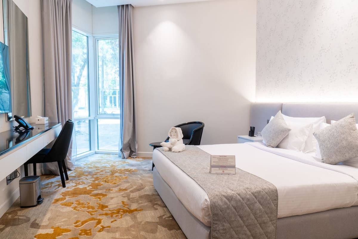 A hotel room with a bed, a desk, a chair, and a television.