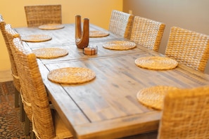 A wooden dining table with woven placemats and wicker chairs.