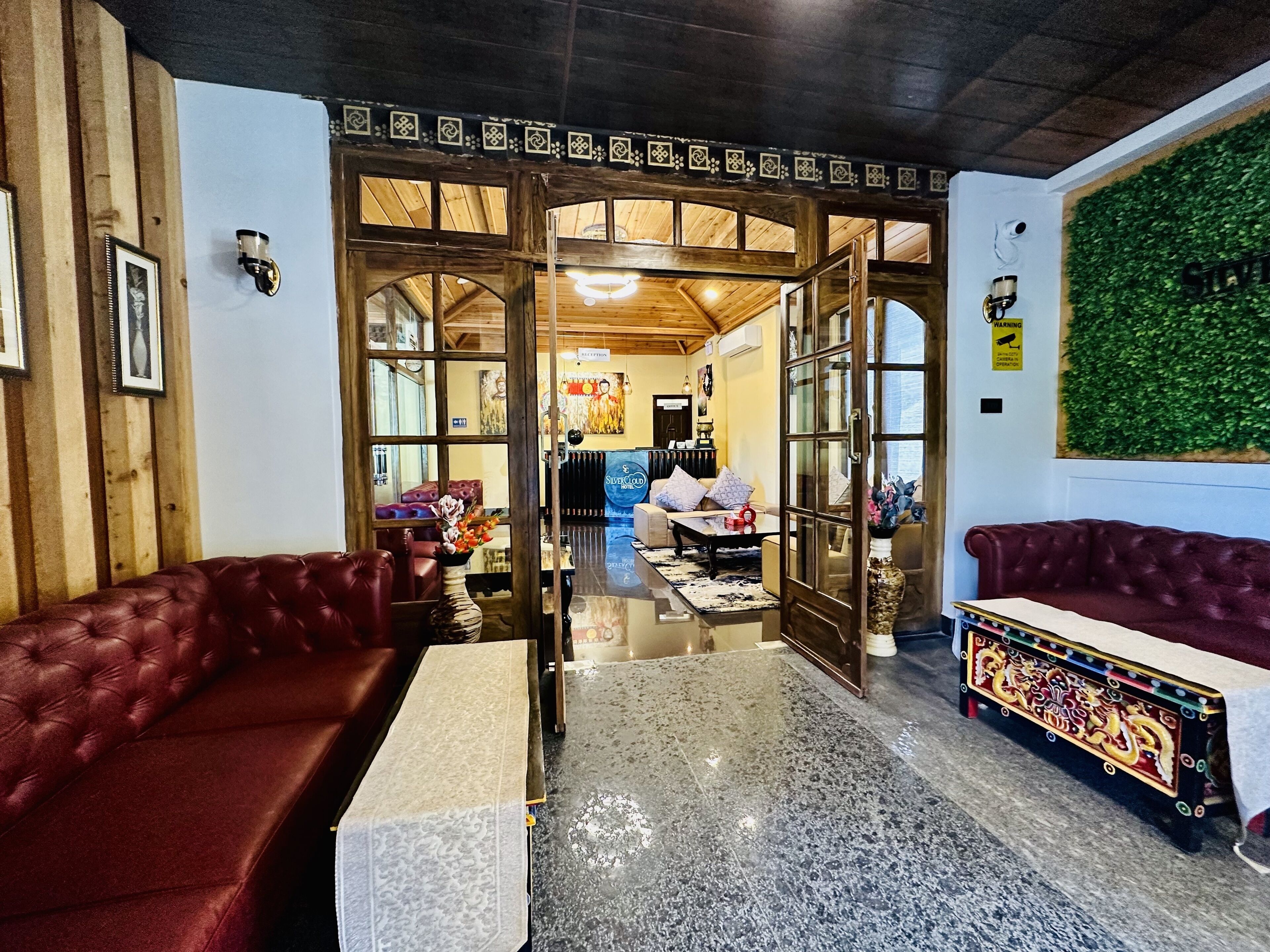Un intérieur chaleureux avec un plafond en bois, un canapé en cuir rouge, une table basse à motifs et un banc décoratif.