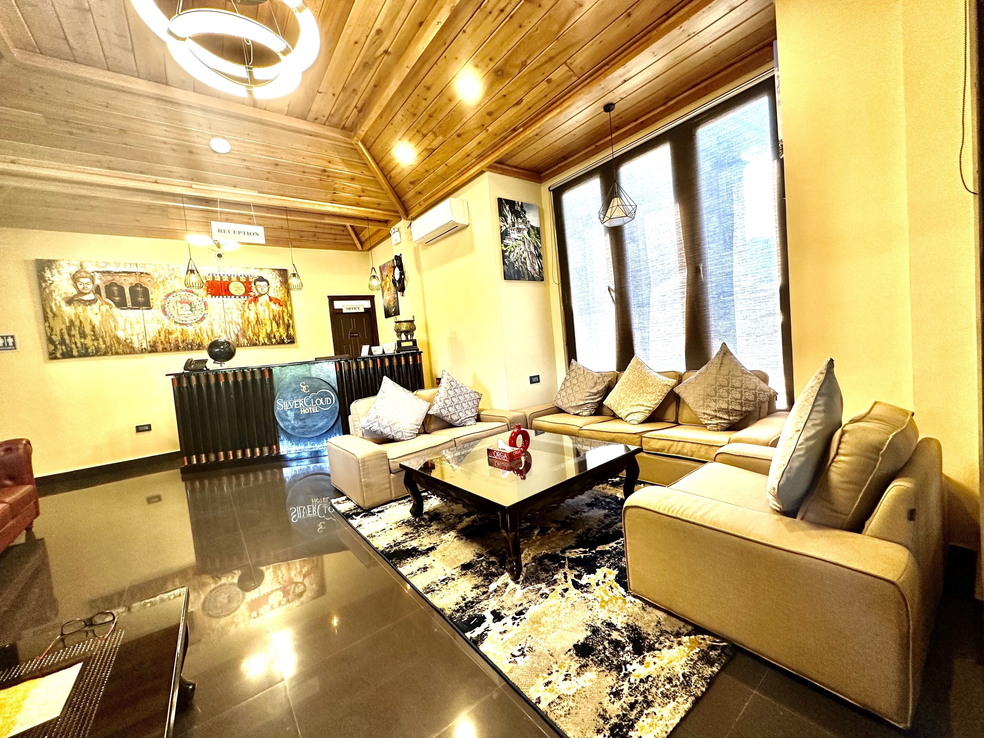 A spacious living area with a sofa set, a glass coffee table, and a reception desk.