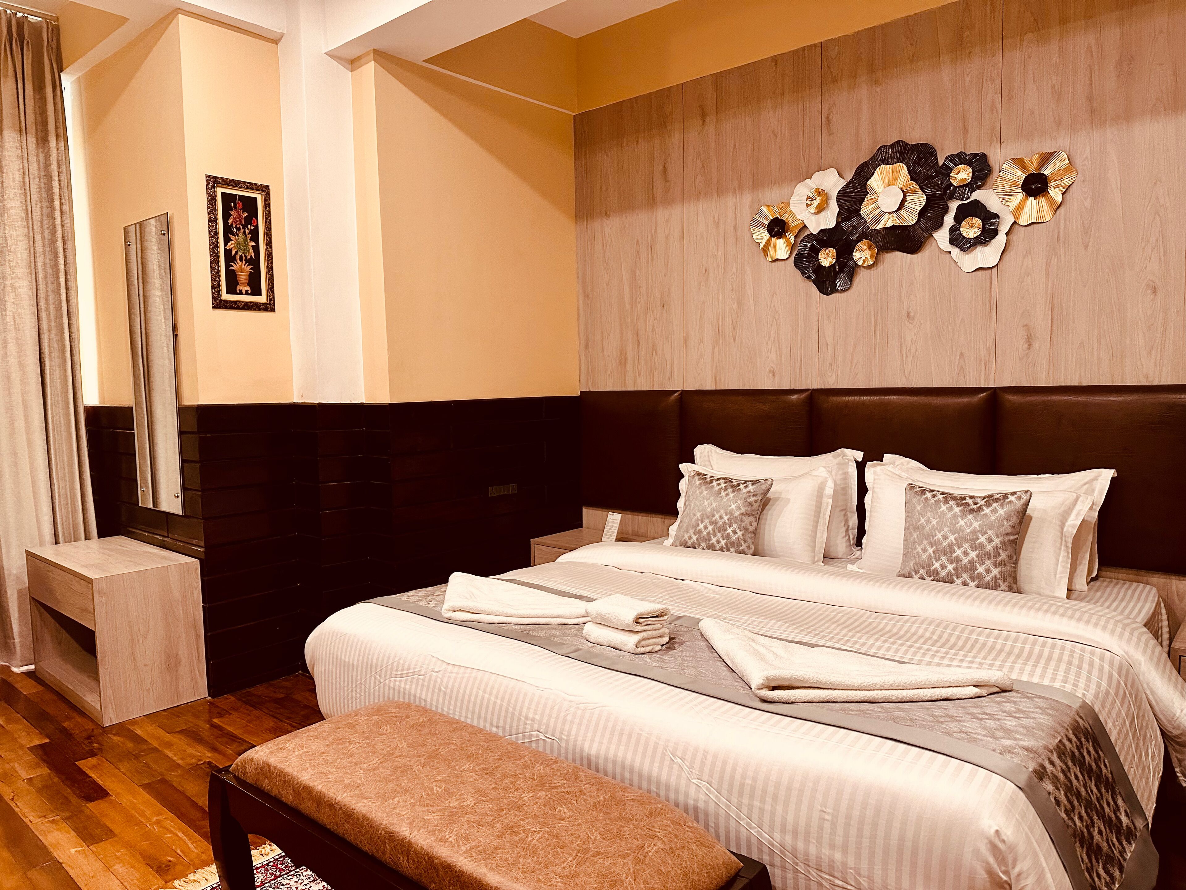 A modern bedroom with a large bed, a bench, and a decorative wall piece.