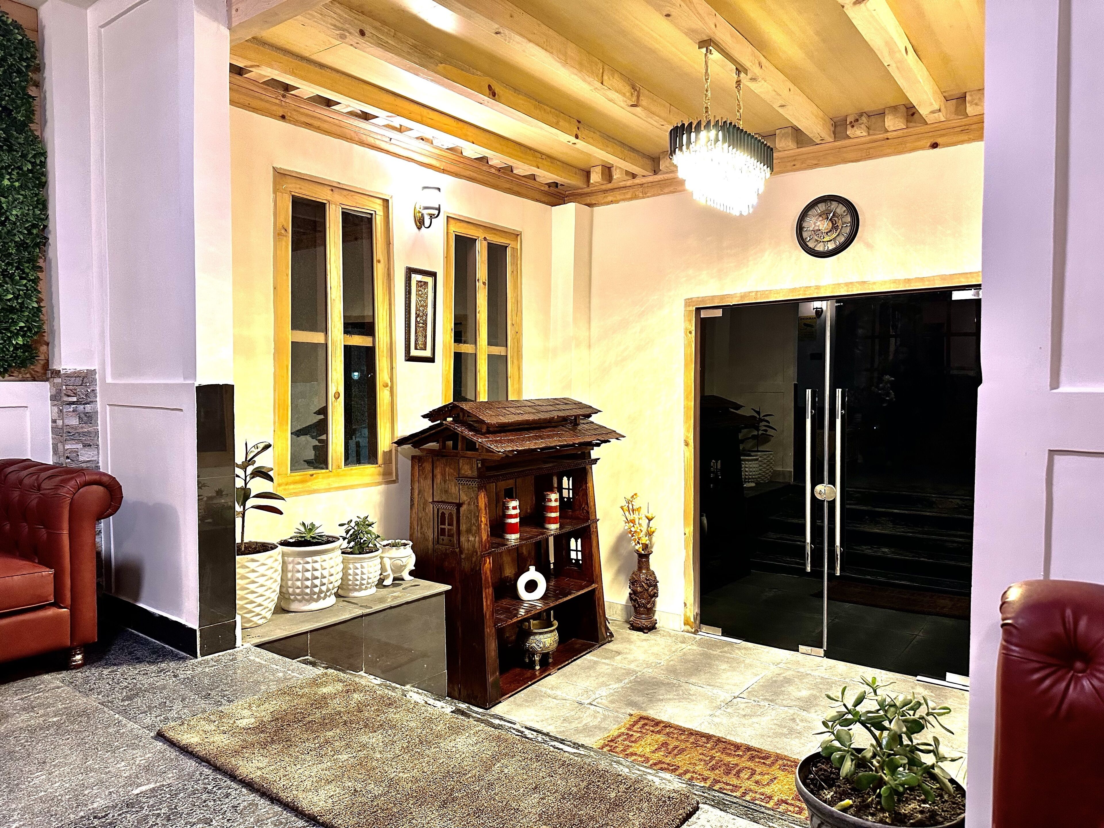 A cozy living room with a wooden ceiling, a large window with multiple panes, a small wooden model house, and a glass door leading outside.