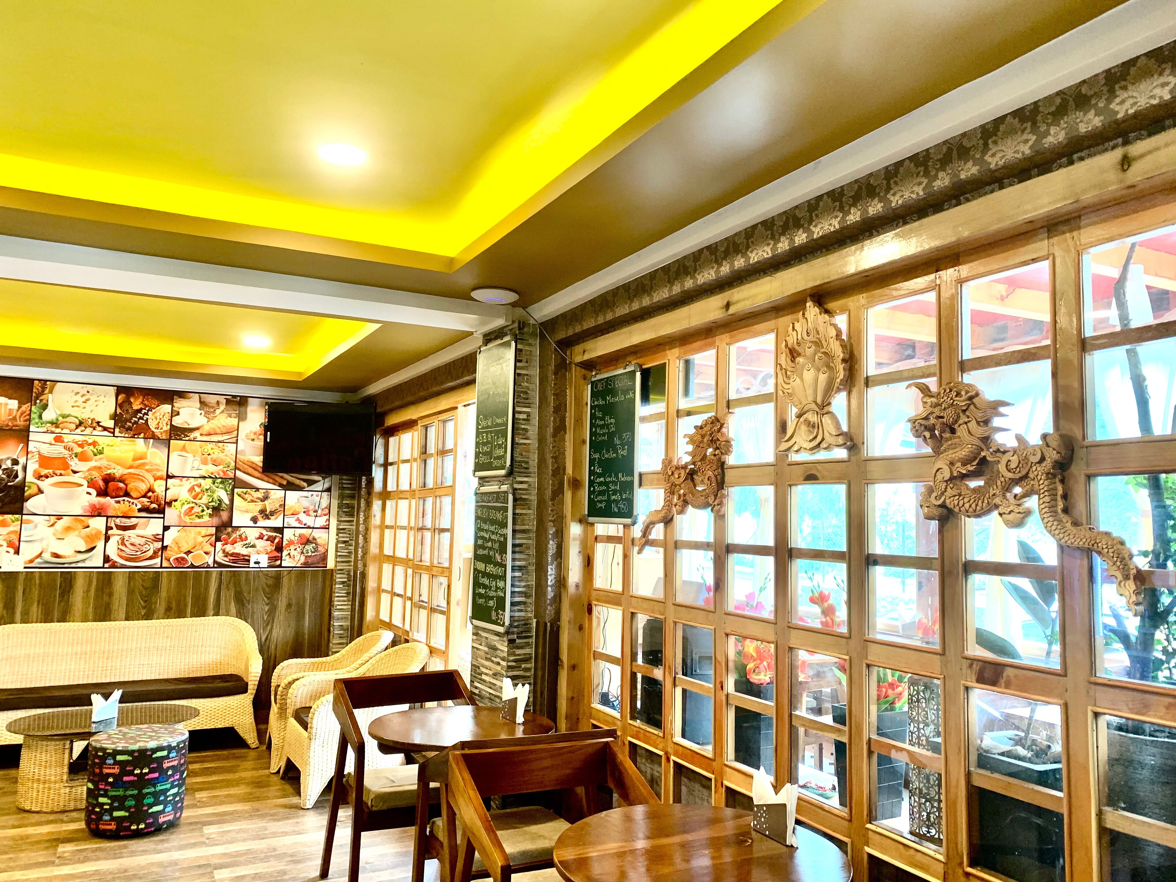 A restaurant interior with a wooden ceiling, a wall of food images, and decorative dragon carvings.