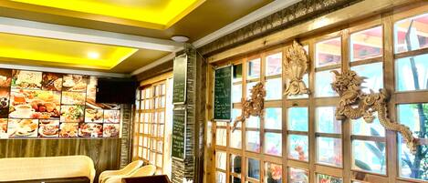 A restaurant interior with a wooden ceiling, a wall of food images, and decorative dragon carvings.