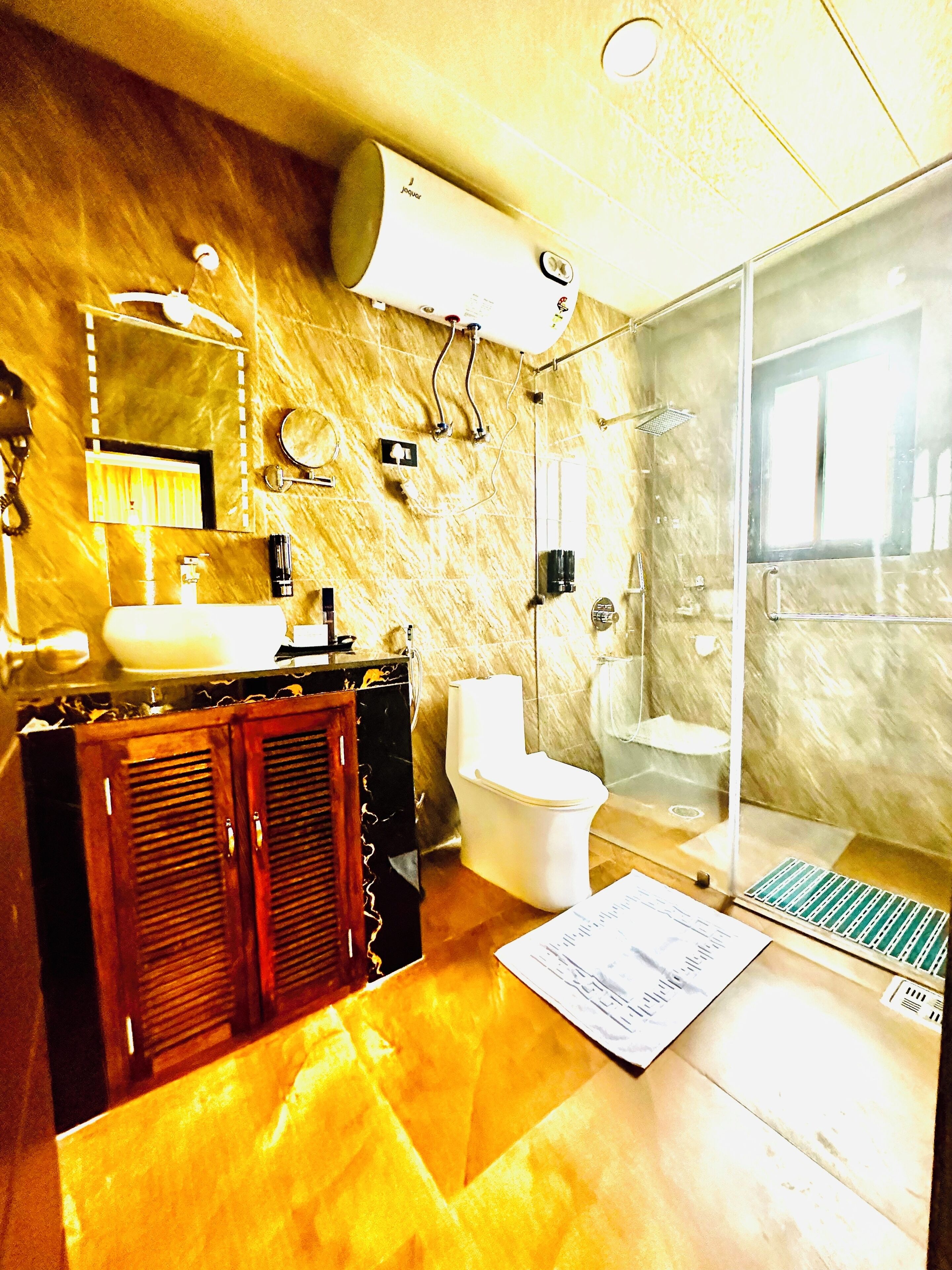 Un baño con encimera de mármol, lavabo, inodoro, cabina de ducha y espejo.