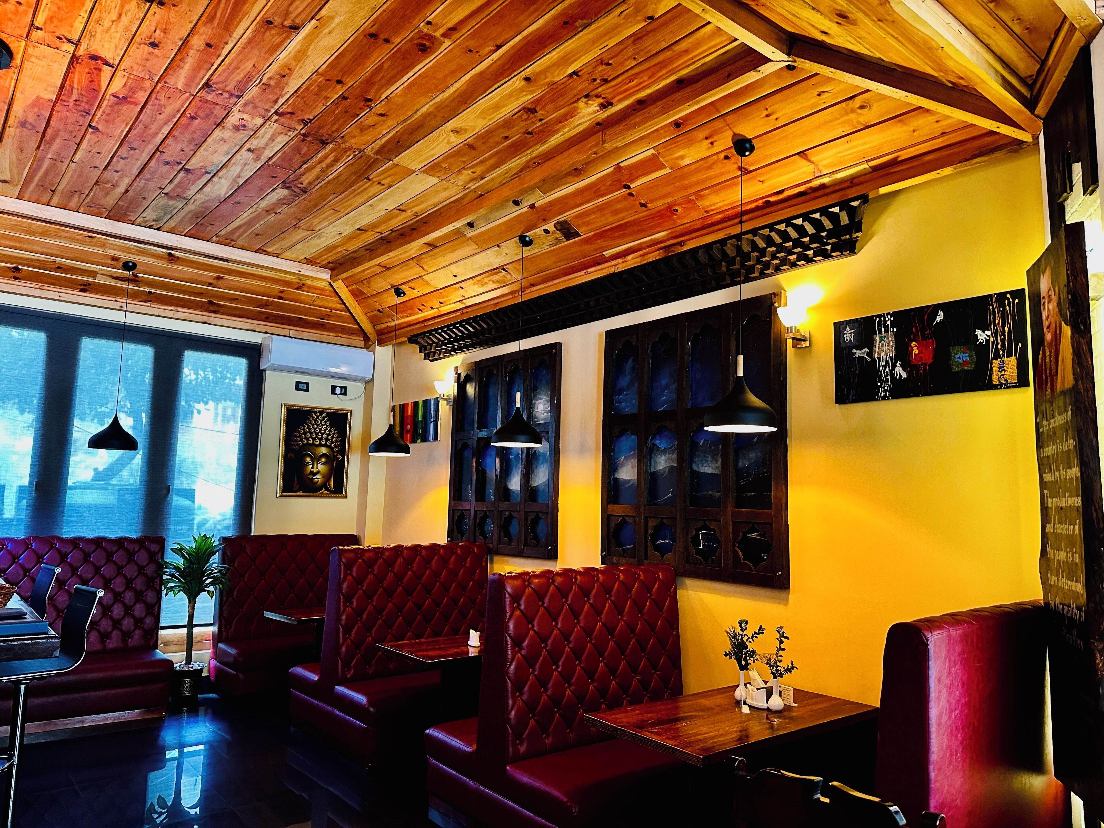 A restaurant interior with wooden ceiling beams, red cushioned booths, and large windows.