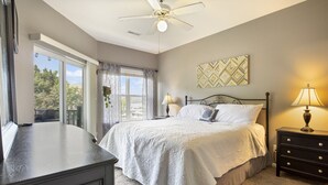 Une chambre à coucher avec un lit, des lampes de chevet, un ventilateur de plafond et une fenêtre avec des rideaux.