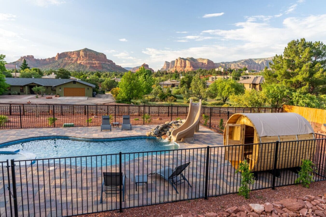 A backyard with a swimming pool, a slide, and a covered wooden structure.