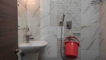 Ein Badezimmer mit Waschbecken, Spiegel, Dusche und einem roten Eimer.