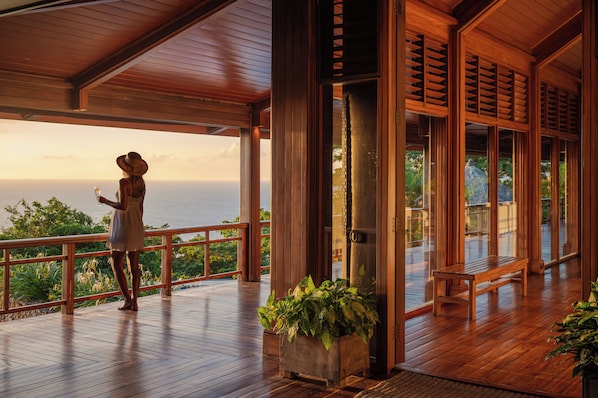 A wooden deck with a view of the ocean, a bench, and a potted plant. - Wakaya Island Resort & Spa (Wakaya Island)