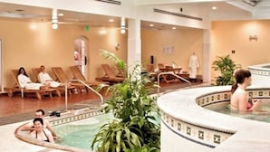 Un hall d’hôtel avec un espace piscine, des chaises longues et un espace dédié aux soins de spa.