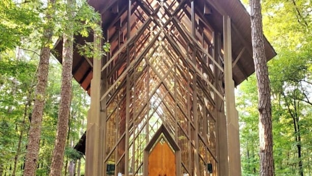 Une structure en bois dotée d’une grande porte centrale, entourée d’arbres.