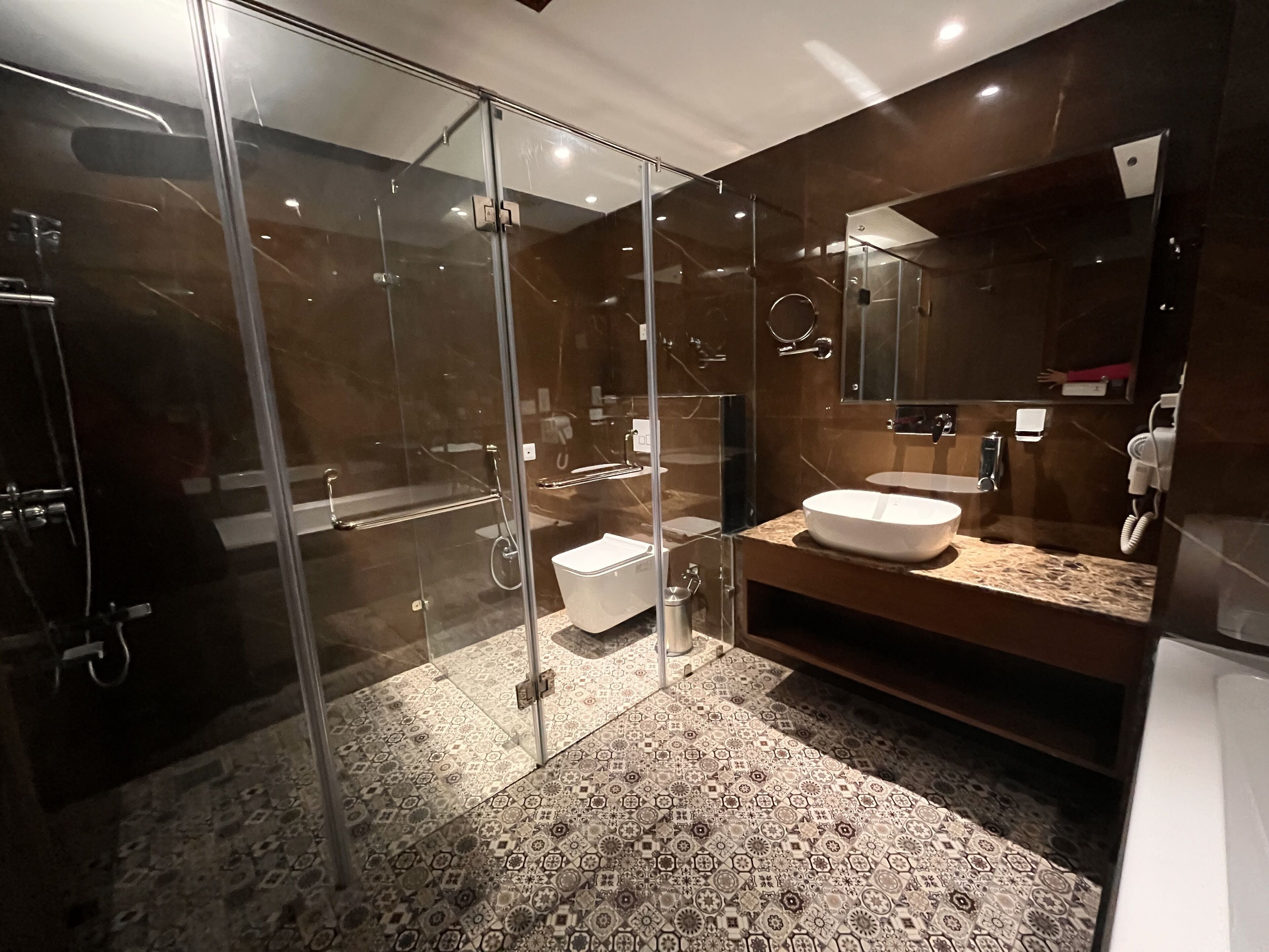 A modern bathroom with a glass-enclosed shower, a white sink, and a large mirror.