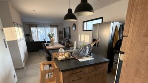 Una cocina moderna con armarios de madera, una isla central, iluminación colgante y un refrigerador.