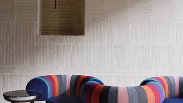 Un intérieur moderne avec un mur en briques, une petite fenêtre et des sièges colorés recouverts de tissu.
