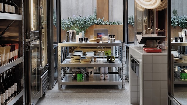 Una cocina moderna con electrodomésticos de acero inoxidable, gabinetes de vidrio y una isla central con una lámpara colgante.