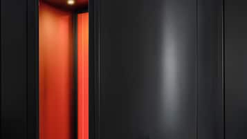 A modern, minimalist room with a curved black wall, a red carpeted area, and a metallic chair.