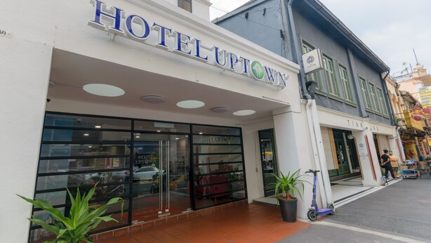 Entrada de un hotel con un letrero que dice "HOTEL UPTOWN" y una puerta de acceso visible.