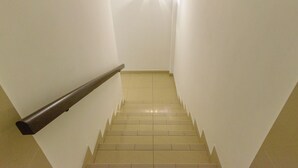 Una escalera con barandilla que conduce a un rellano con una lámpara.