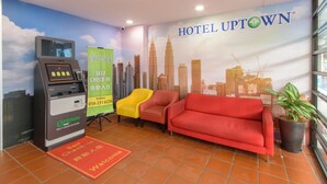 Un quiosco de autoservicio, un sofá rojo y un mural con un paisaje urbano en el vestíbulo de un hotel.