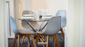 A dining table set with plates, glasses, and cutlery, surrounded by modern chairs. - Haywood by Central Serviced Apartments (Dundee City Council)