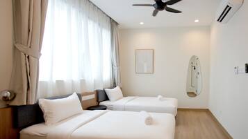 A hotel room with two beds, a ceiling fan, an air conditioning unit, a bedside table, a nightstand, a mirror, and a window with curtains.