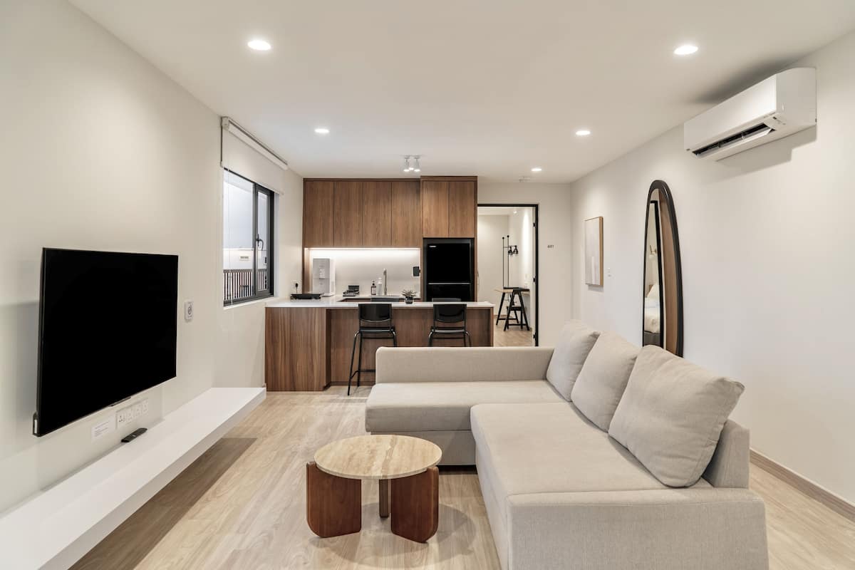 A modern living room with a flat-screen TV, a beige sofa, and a small wooden coffee table.