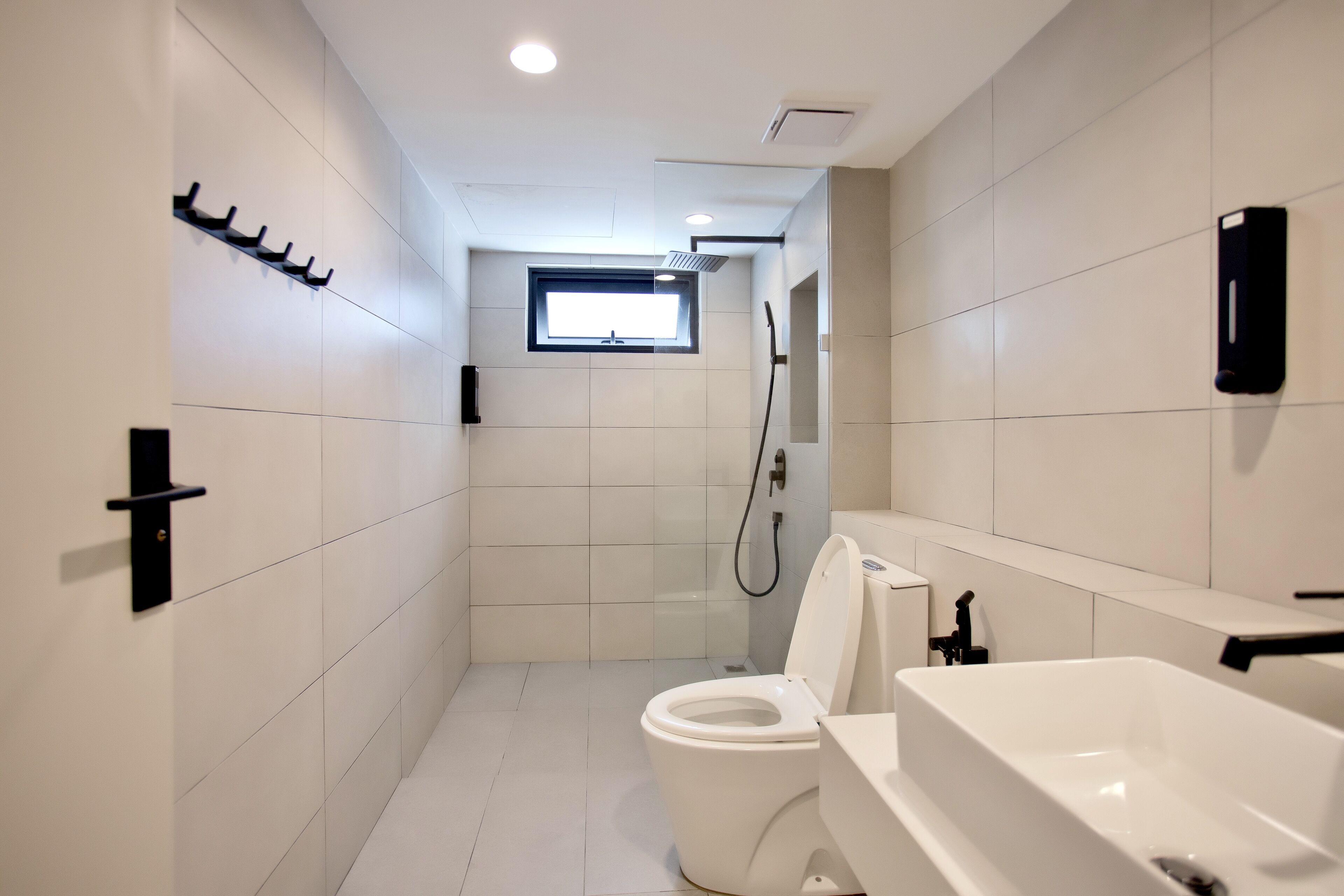 A modern bathroom with a toilet, a shower, and a sink.