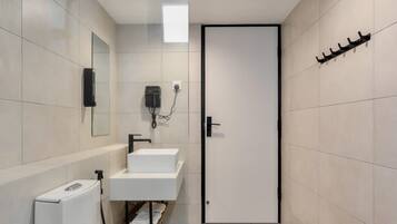 Un baño moderno con inodoro, dos lavamanos, un espejo y una puerta.