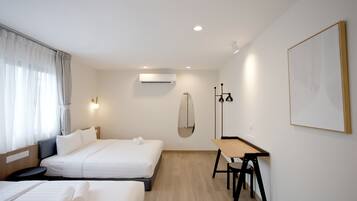 A hotel room with two beds, a desk, and a large mirror.