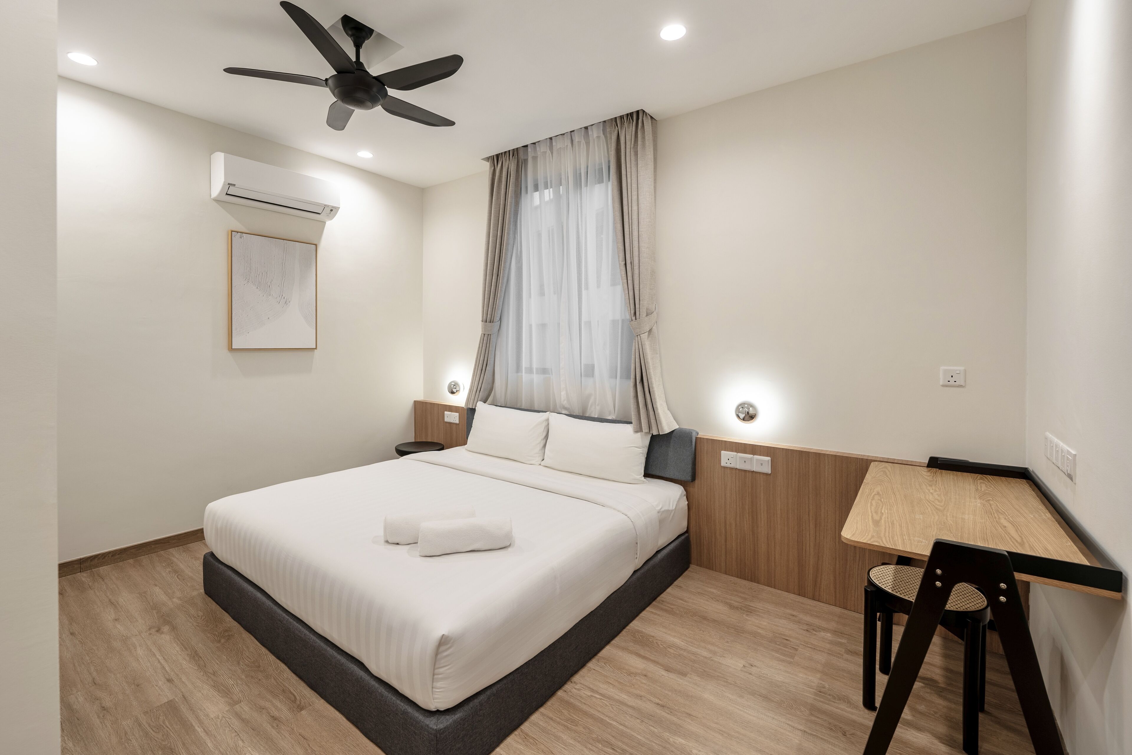 A modern hotel room with a bed, a desk, and a chair.