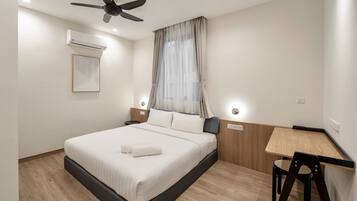 A modern hotel room with a bed, a desk, and a chair.