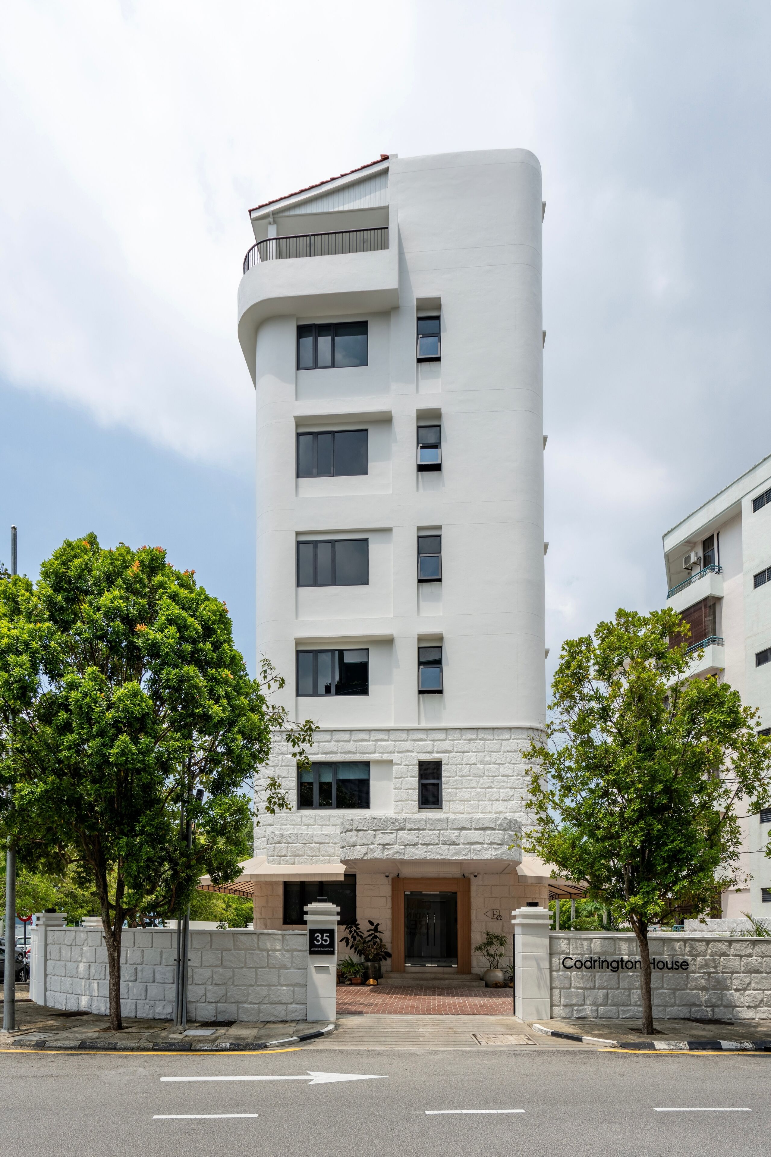 Een modern gebouw met een gebogen gevel, meerdere ramen en een stenen fundering.