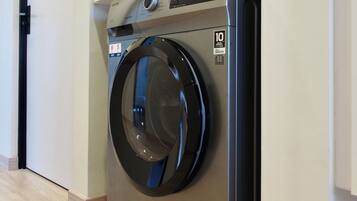 Een voorlader wasmachine in een hotelkamer met een houten vloer en witte muren.