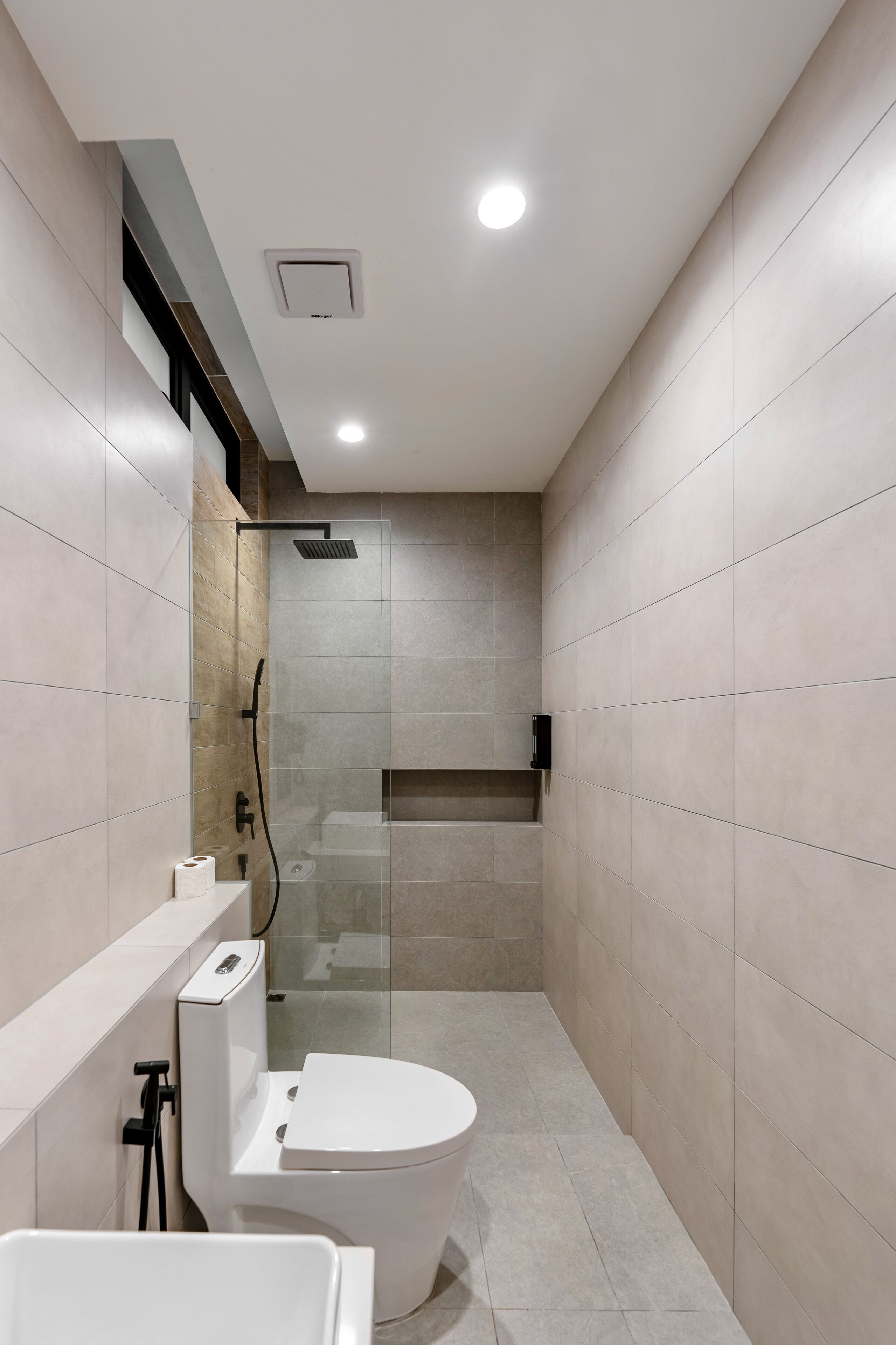 A modern bathroom with a toilet, shower, and a built-in sink.