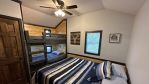 A bedroom with a bunk bed, a single bed, a ceiling fan, and a wooden door. - FS Rental #4 Annapolis, MO Black River (Annapolis)